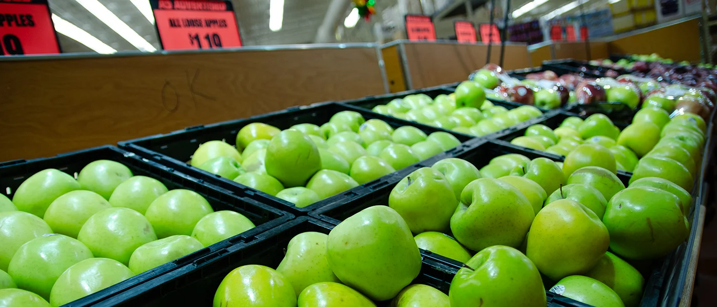 a bunch of green apples on a shelf at Fresh County Market